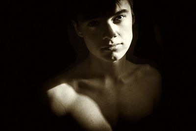 Portrait of shirtless teenage boy in darkroom