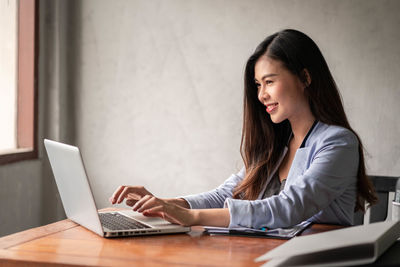 Young woman using phone while sitting on table