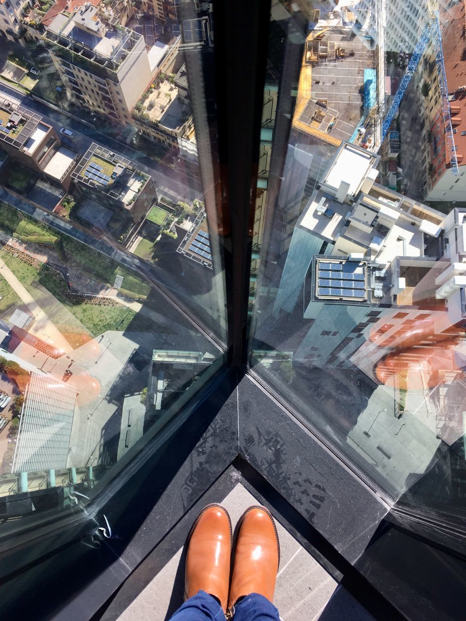 LOW SECTION OF MAN WALKING ON GLASS WINDOW