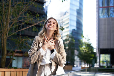 Portrait of young woman using mobile phone in city