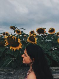 Side view of woman standing against sunflowers