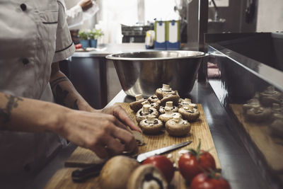 Midsection of female chef cutting mushrooms at kitchen counter