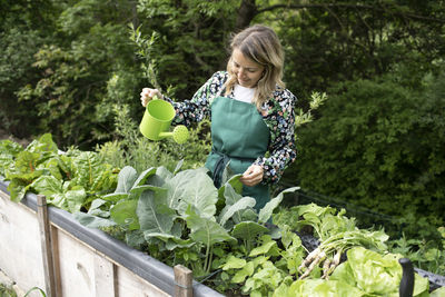 Rear view of woman sitting by plants