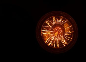 Close-up of illuminated light bulb against black background