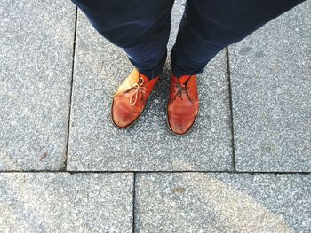 Low section of person wearing shoes standing on footpath