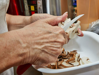 Woman cuts mushrooms on wooden cutting board. cooks according to the recipe at home in the kitchen