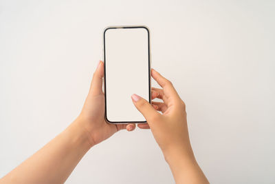 Close-up of hand holding smart phone against white background