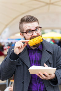 Portrait of man eating corn outdoors