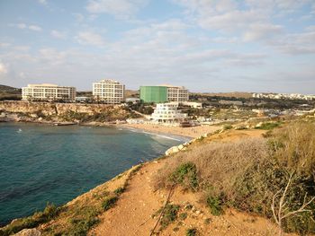 Scenic view of sea by buildings against sky