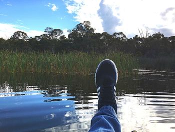 Low section of man standing by lake against sky