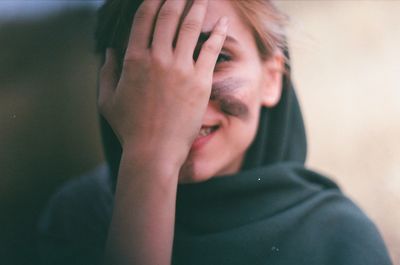 Close-up of woman covering face with hand outdoors