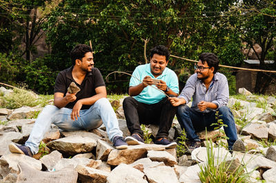 Smiling young friends sitting on rocks