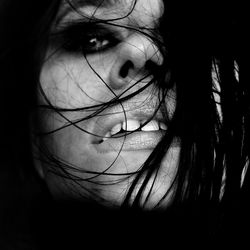 Close-up of seductive woman with messy hair against black background