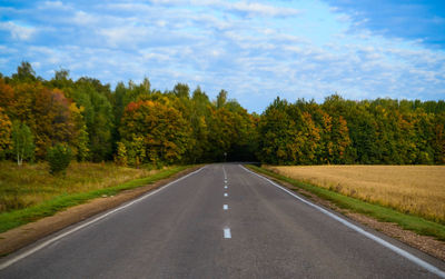 Road amidst trees against sky during autumn