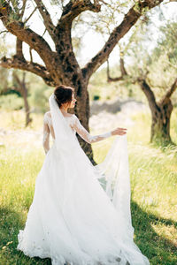 Rear view of woman with arms raised on tree