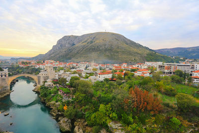 Aerial view of townscape by mountain against sky