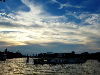 Silhouette of boats in sea against cloudy sky