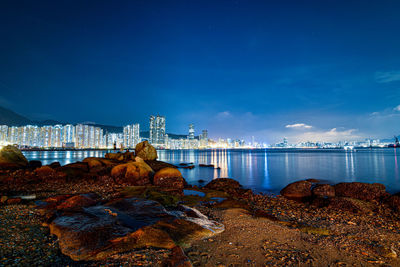 Sea and buildings in city against blue sky