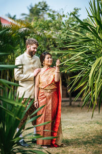 Young couple standing against plants