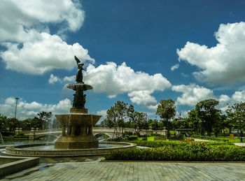 Statue in park against cloudy sky