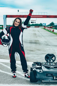 Full length portrait of young woman standing on road