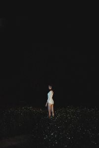 Woman standing on field against sky at night