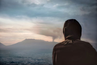 Rear view of man looking at cityscape against sky