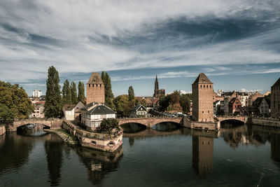 Bridge over river by buildings against sky in city