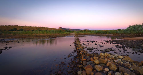 Scenic view of river against sky at sunset