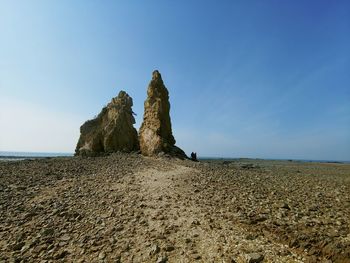 Rock formations at beach against clear blue sky