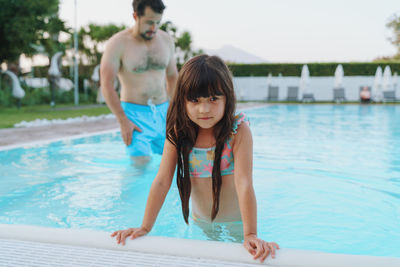Portrait of girl swimming in pool with father