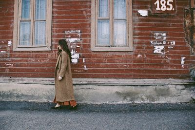 Full length of woman standing on street against building