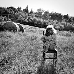 Woman sitting on chair on field