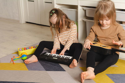 Happy children playing musical instruments at home. sisters have fun in the room
