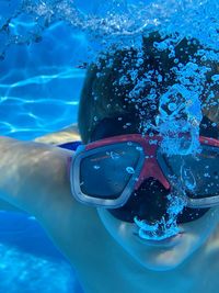 Portrait of cute boy wearing swimming goggles while swimming in sea