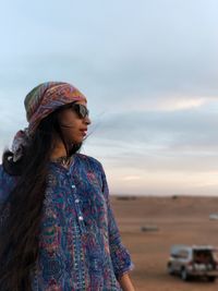 Young woman standing against sky during sunset