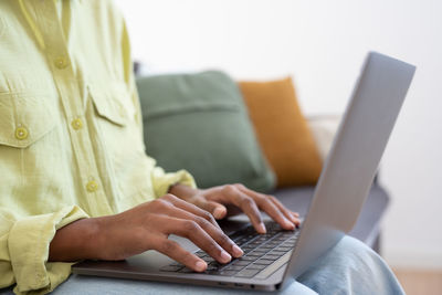 Midsection of woman using laptop at table