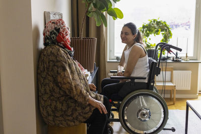 Side view of woman with paraplegia talking to mother at home