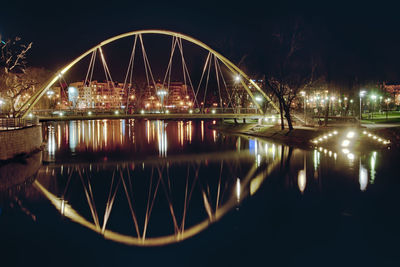 Illuminated bridge over river against sky in city at night