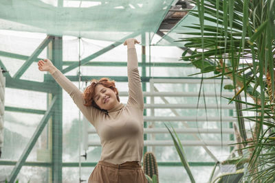 A beautiful plus size girl enjoying standing among the green plants