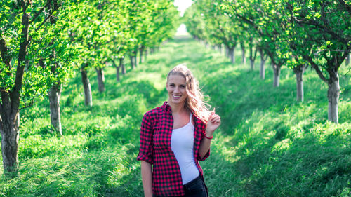 Portrait of smiling young woman standing against trees