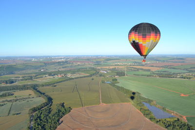 Hot air balloons flying over landscape against clear sky