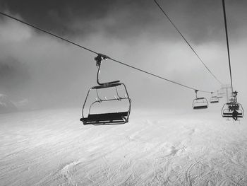 Ski lift over snowy mountain against sky