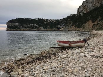 Boat moored on shore at beach against sky