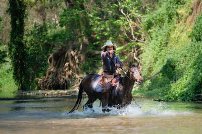 Young man riding horse in river