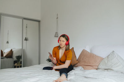 Portrait of young woman sitting on bed