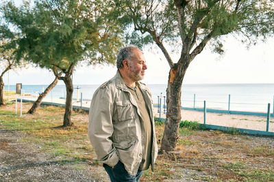 Happy middle-aged bearded man walking along promenade seaside. concept of leisure activities