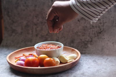 Cropped image of man holding fruits in bowl on table