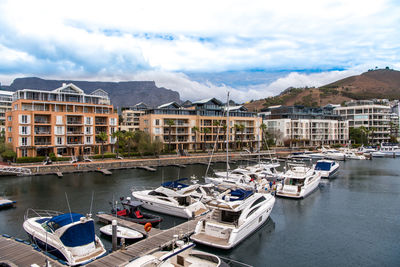 Boats moored at harbor against sky