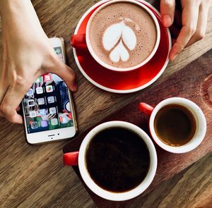 Close-up of woman holding coffee cup on table